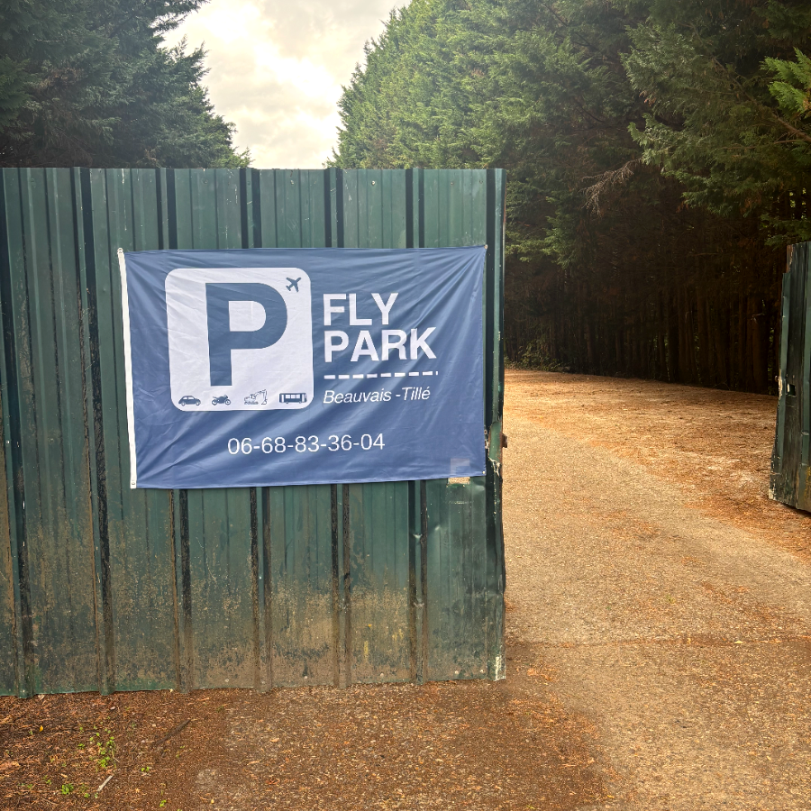 Portail d'entrée du parking Fly Park avec la bâche au logo et le numéro de téléphone