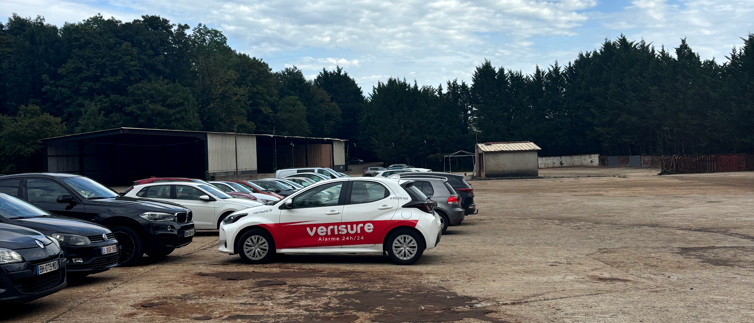 Véhicules de clients stationnés sur le terrain privé de Fly Park Beauvais, sous un ciel nuageux